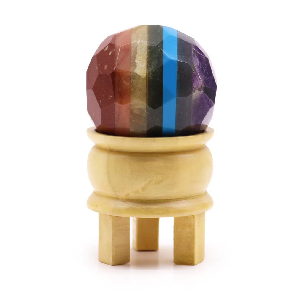 Sferă decorativă fațetată cu benzi multicolore, așezată pe suport din lemn deschis